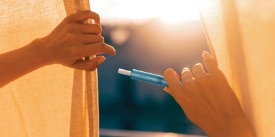 Hands holding a Pebble Beige IQOS ILUMA device.